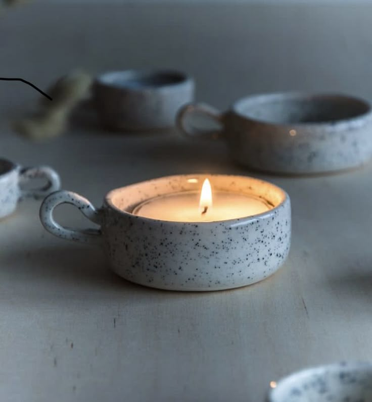 a candle that is sitting in some kind of tea light holder on a table with other cups around it