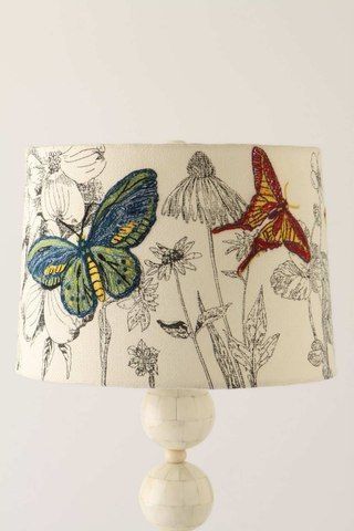 a lamp that is on top of a wooden base with flowers and butterflies painted on the lampshade