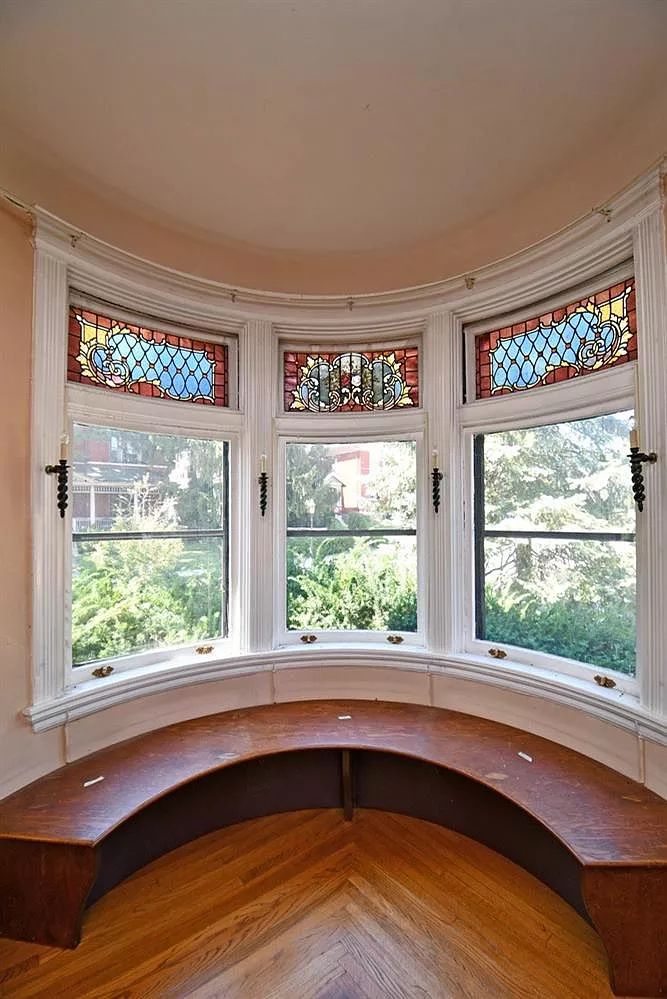 a curved bay window with stained glass in the top half and bottom half, along with wood flooring