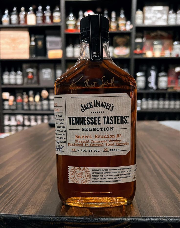 a bottle of whiskey sitting on top of a wooden table next to shelves filled with bottles