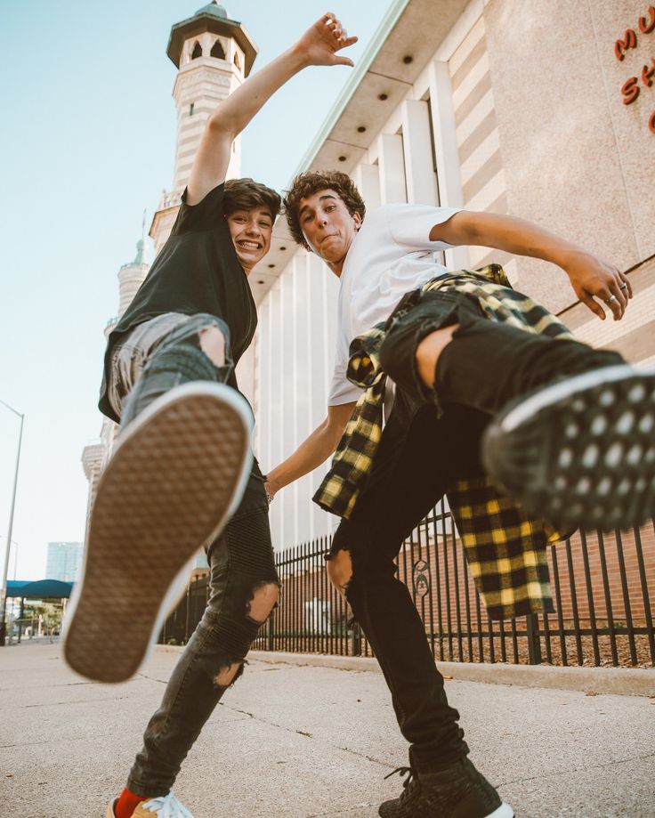 two young men doing tricks on skateboards in front of a building with a clock tower