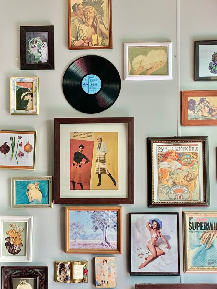 there are many framed pictures on the wall with a vinyl record in front of them