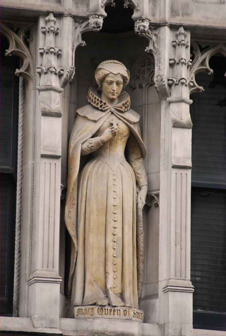 a statue of a woman holding a cross on the side of a building