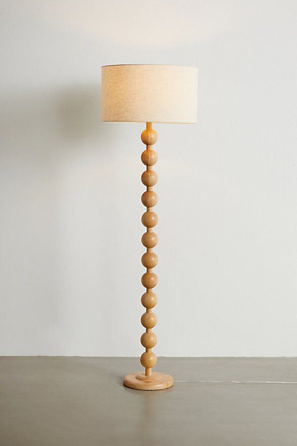 a lamp that is on top of a table with a white wall in the background