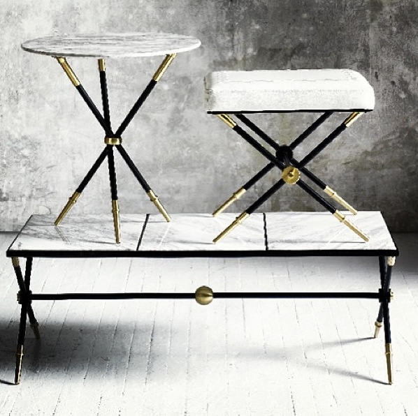 two tables with marble top and metal legs in front of a concrete wall, one is black and the other is white