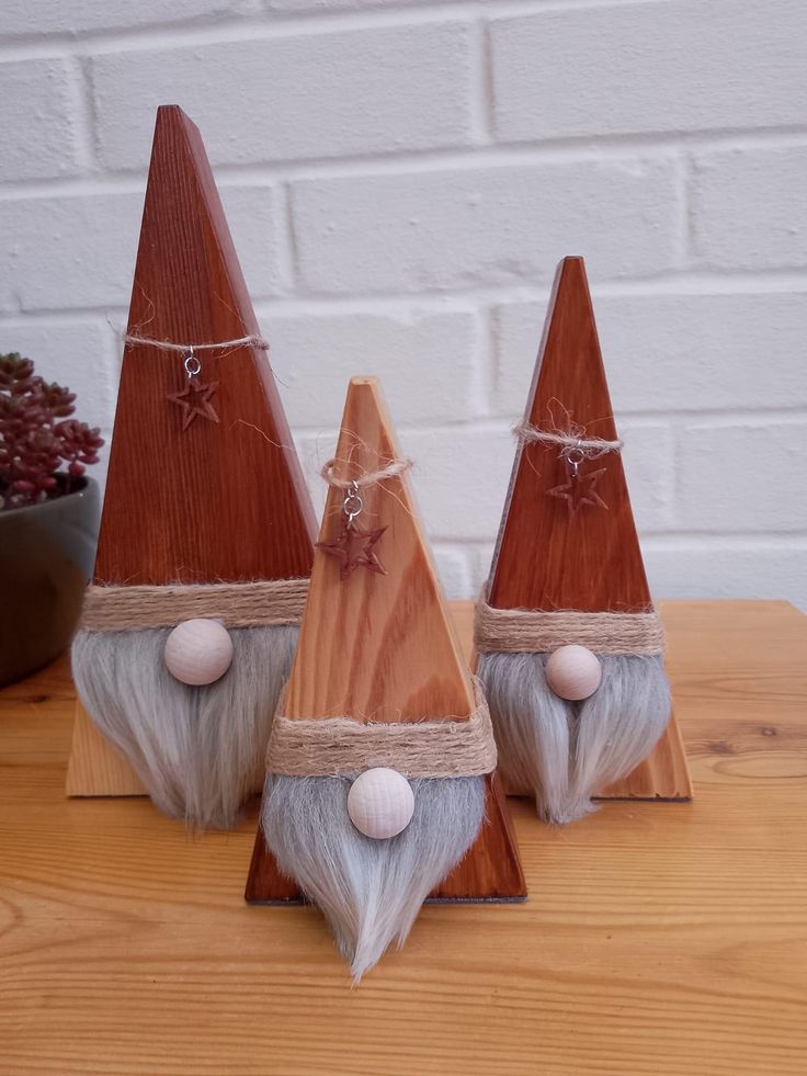 three gnomes made out of wood sitting on top of a table