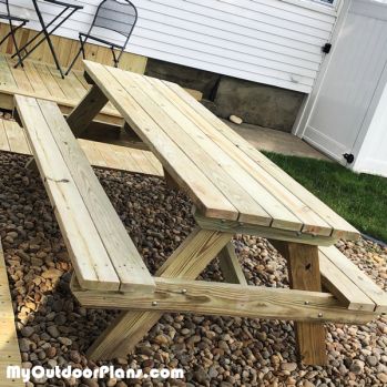 a wooden picnic table sitting on top of gravel