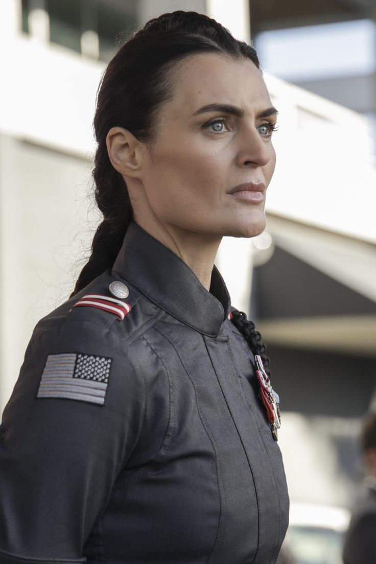 a woman in uniform looking off to the side with an american flag on her chest