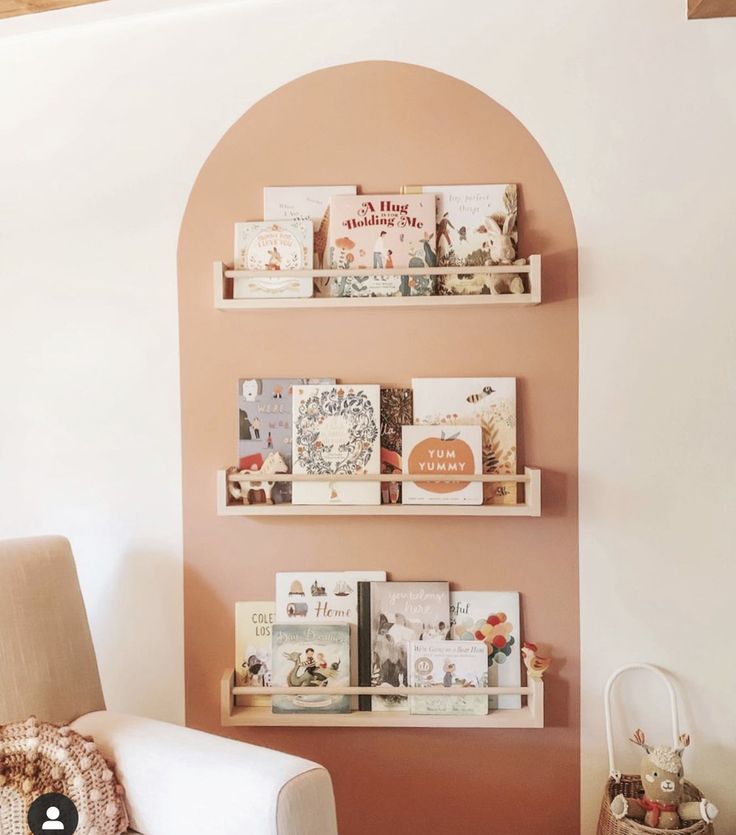 a living room filled with furniture and bookshelves on top of a pink wall