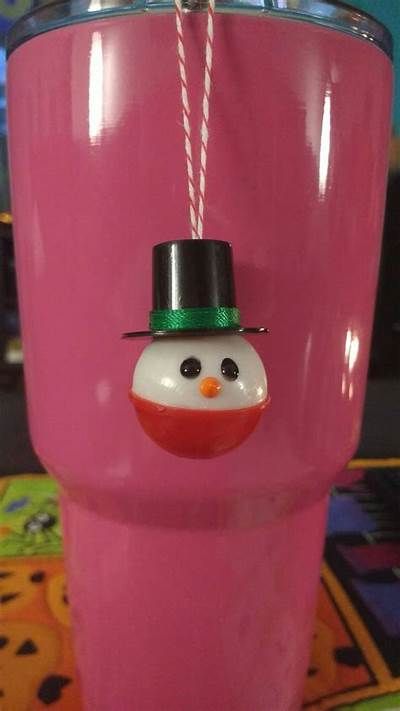 a pink cup with a snowman decoration on the side and a straw sticking out of it