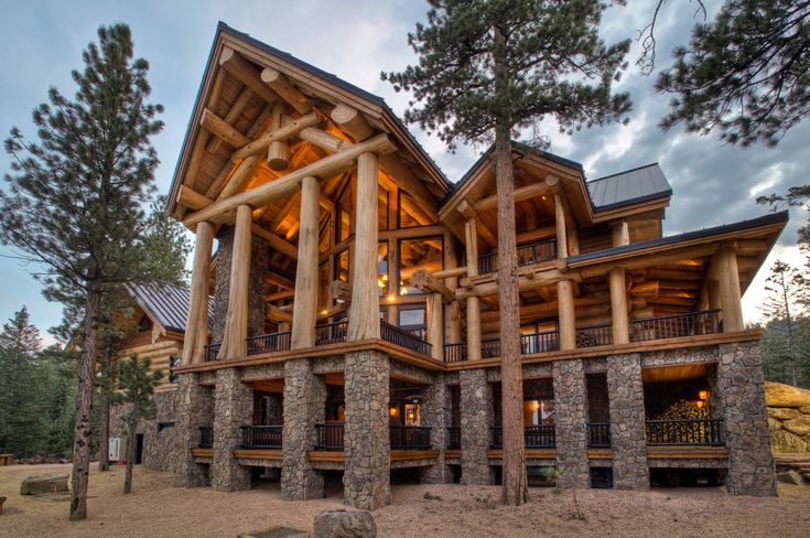 a large log home with lots of windows and stone pillars on the front of it