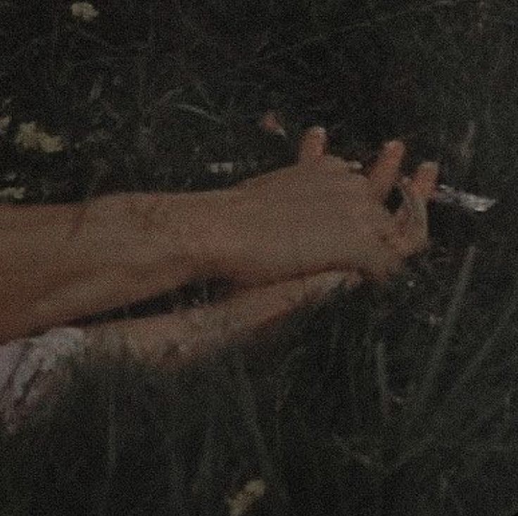 a person with their foot in the grass holding a knife and looking down at them