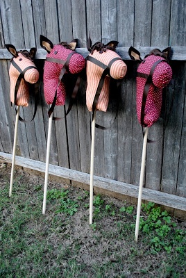 three pink and black cow heads on sticks in front of a wooden fence with grass