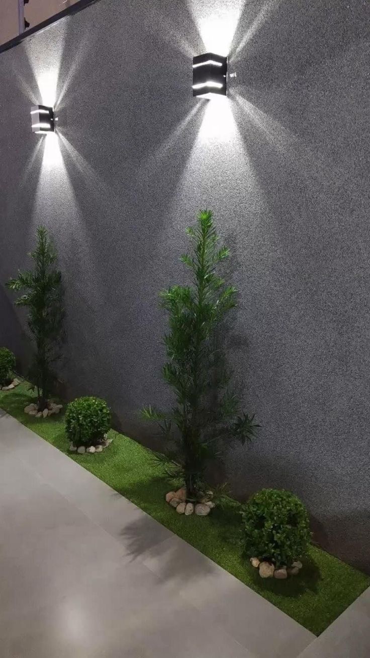 an outdoor wall light that is on the side of a building with grass in front of it