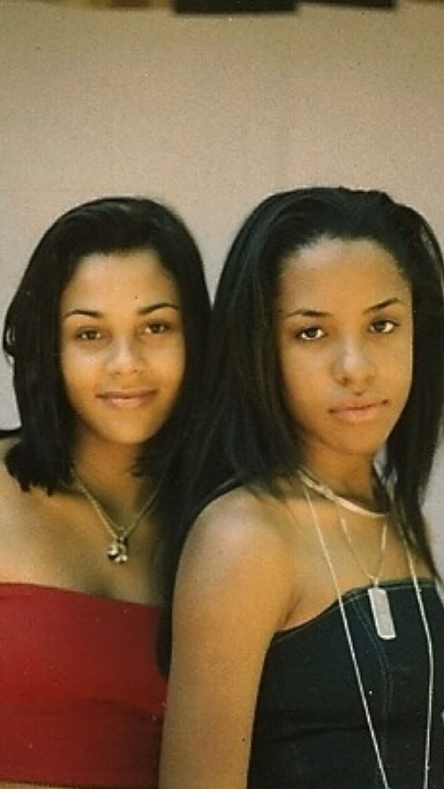 two young women standing next to each other in front of a white wall and wearing necklaces