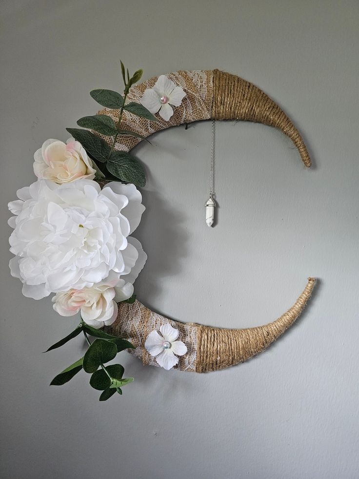 a white flower arrangement is hanging on the wall next to a half moon shaped wreath