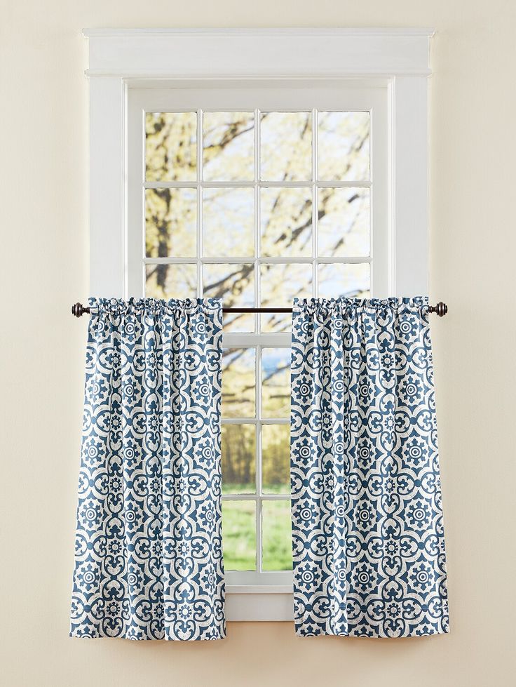 a blue and white window curtain hanging on the side of a wall