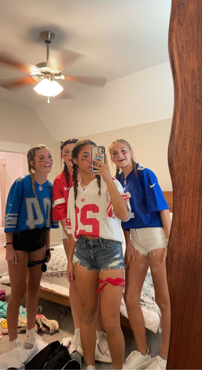 four girls are standing in front of a mirror