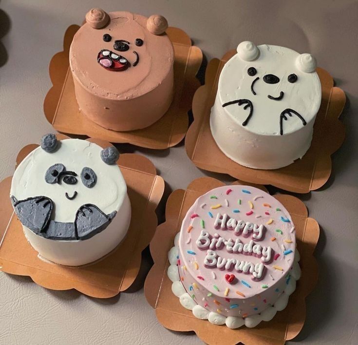 four decorated cakes sitting on top of wooden trays next to each other with faces drawn on them