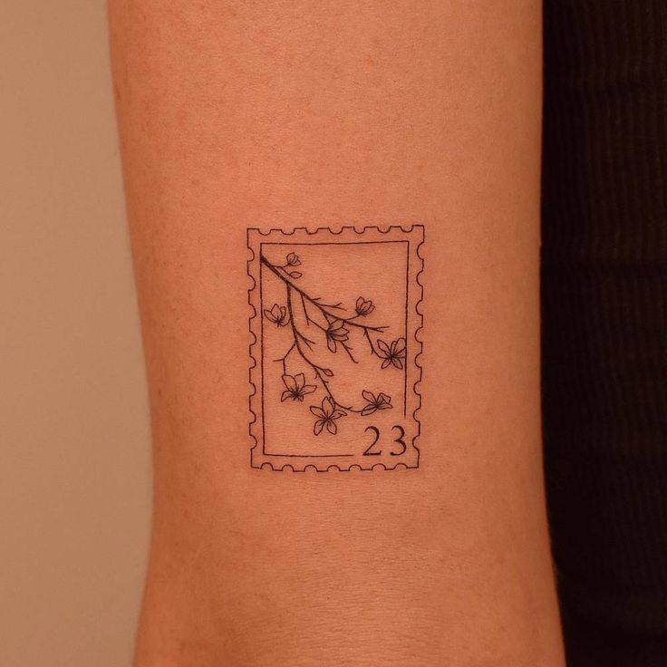 a small tattoo on the arm of a woman's left arm with flowers and leaves