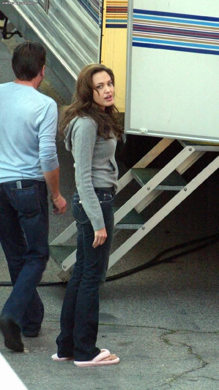 a woman standing in front of a truck next to a man on the sidewalk near an airplane