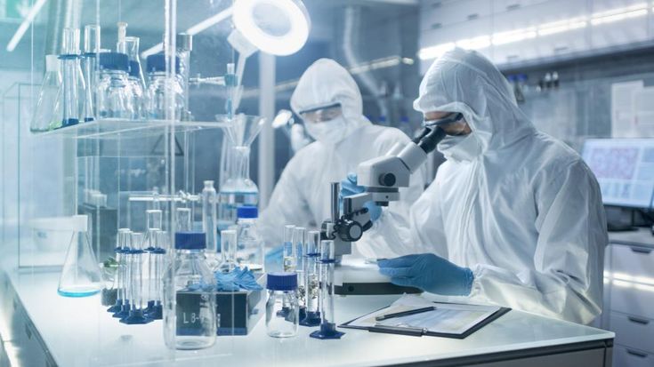 two people in white lab coats are looking through microscopes