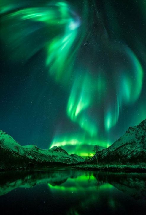 the northern lights shine brightly over mountains and water