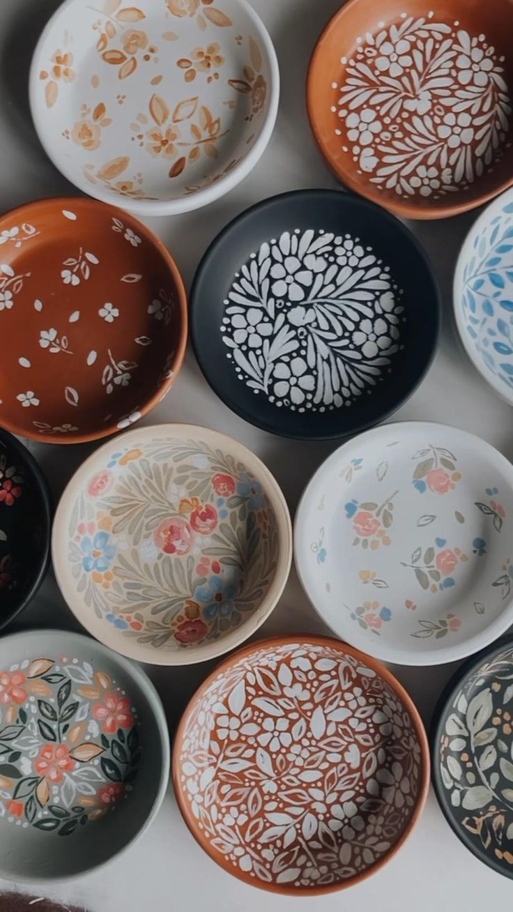 many bowls are lined up together on the table, one is painted with floral designs