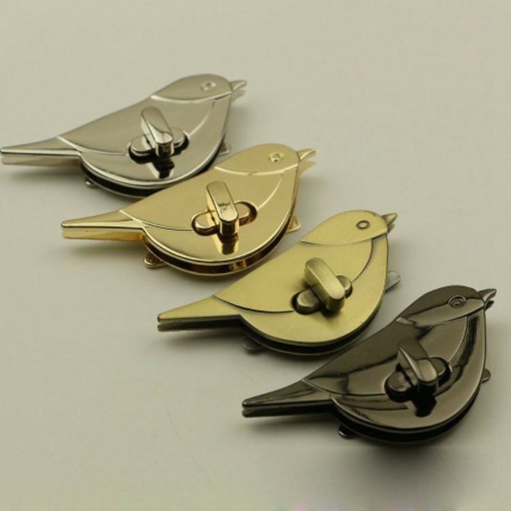 three metal bird shaped key chains on top of each other, one has a gold tone finish and the other is silver