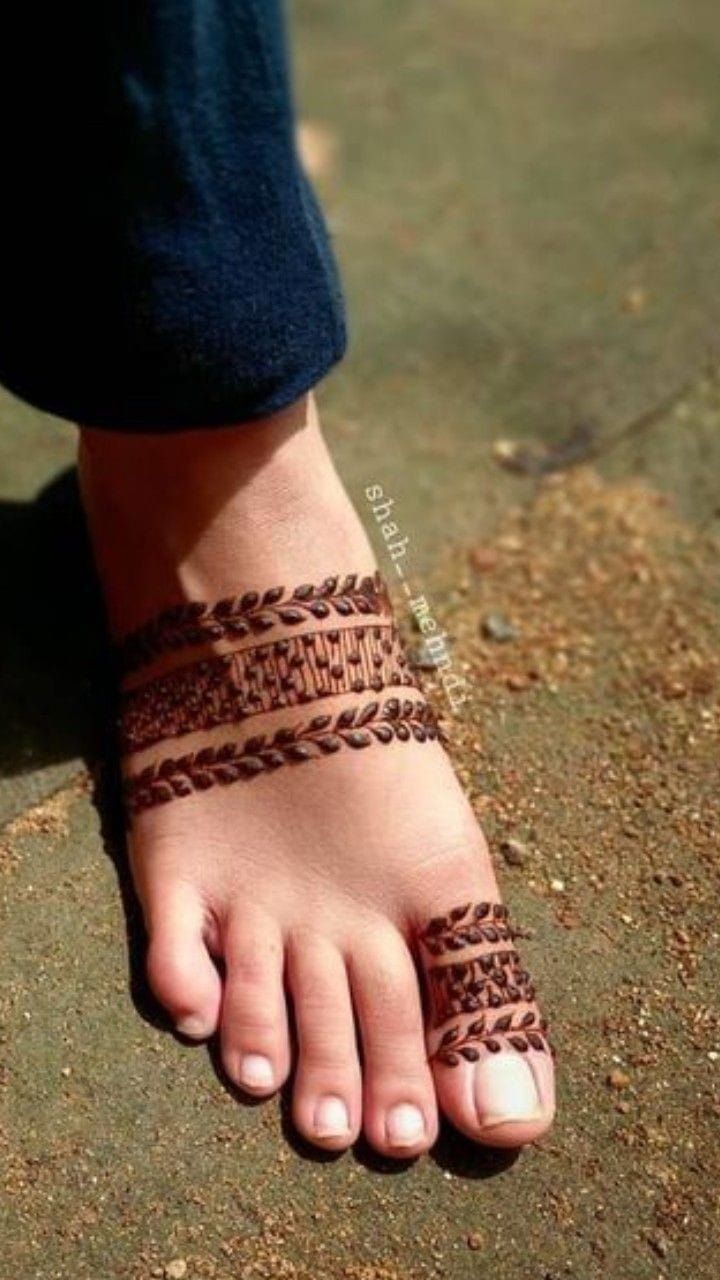 a person's foot with a hendi on it and a bracelet around the toe