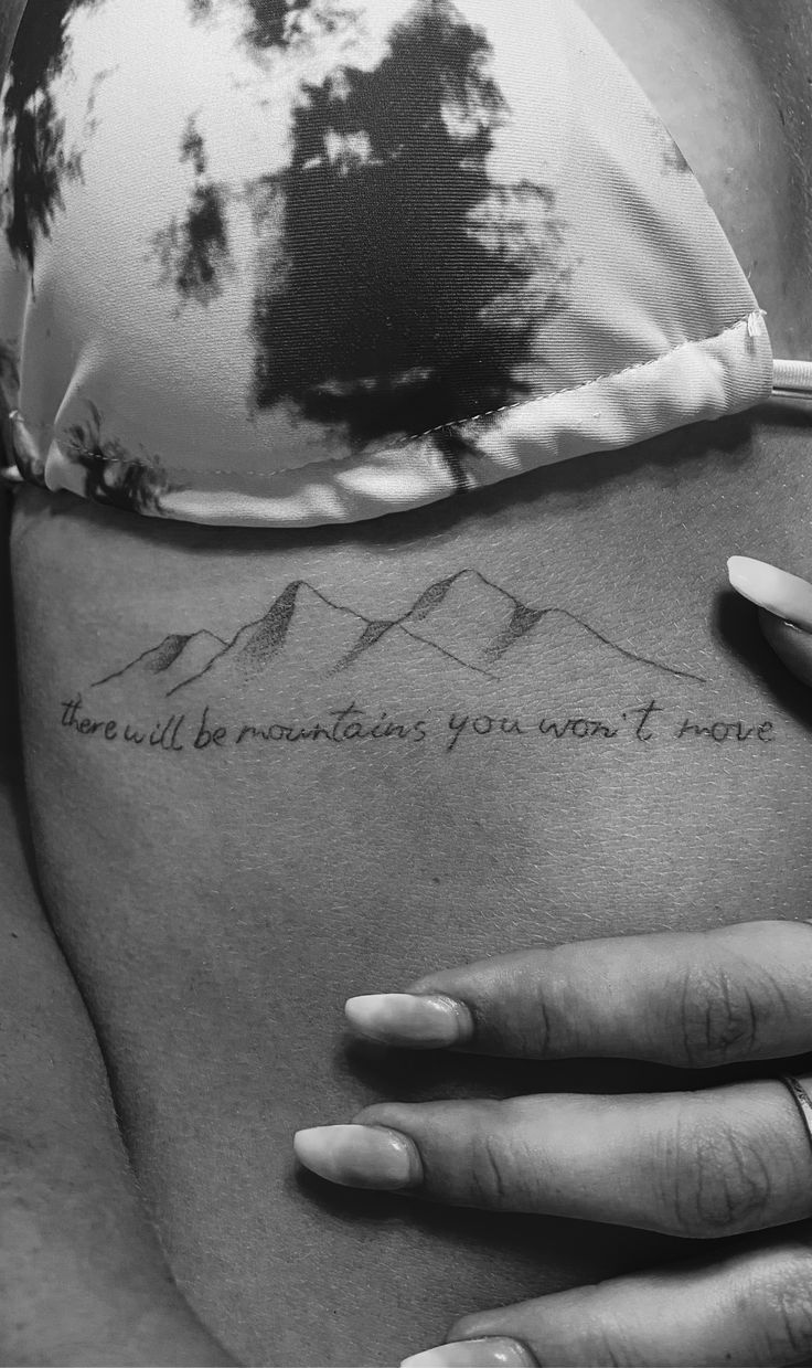 a woman's stomach with mountains and trees on it