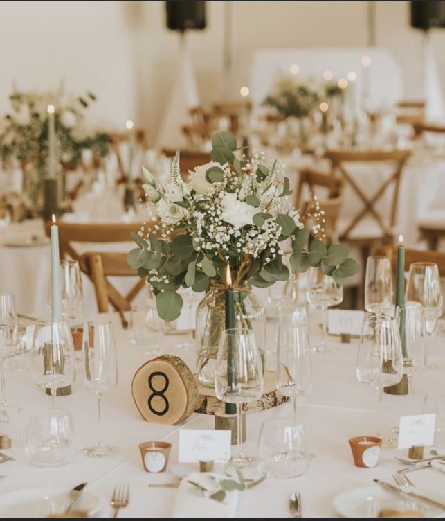 the table is set with white flowers and greenery