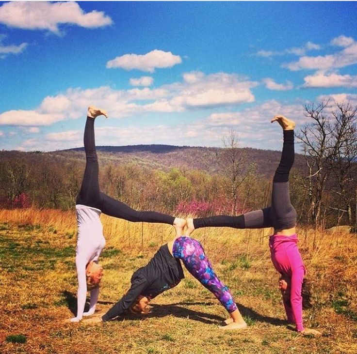 two people doing yoga on top of a hill