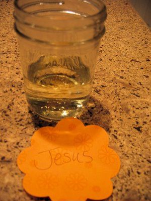 there is a glass cup with the name jesus on it next to an orange coaster