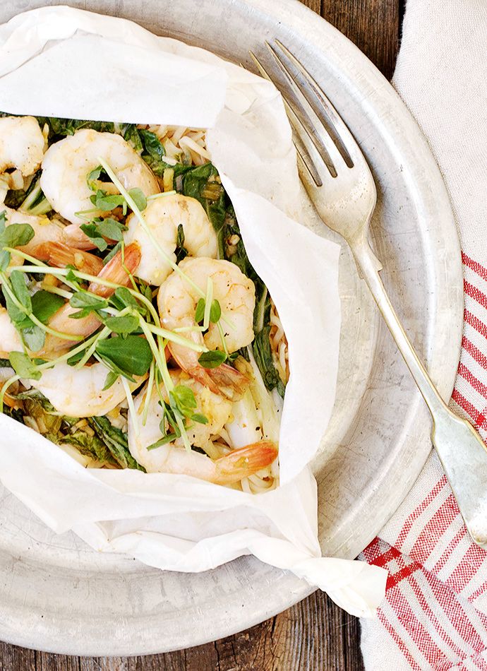 a white plate topped with shrimp and veggies next to a knife and fork