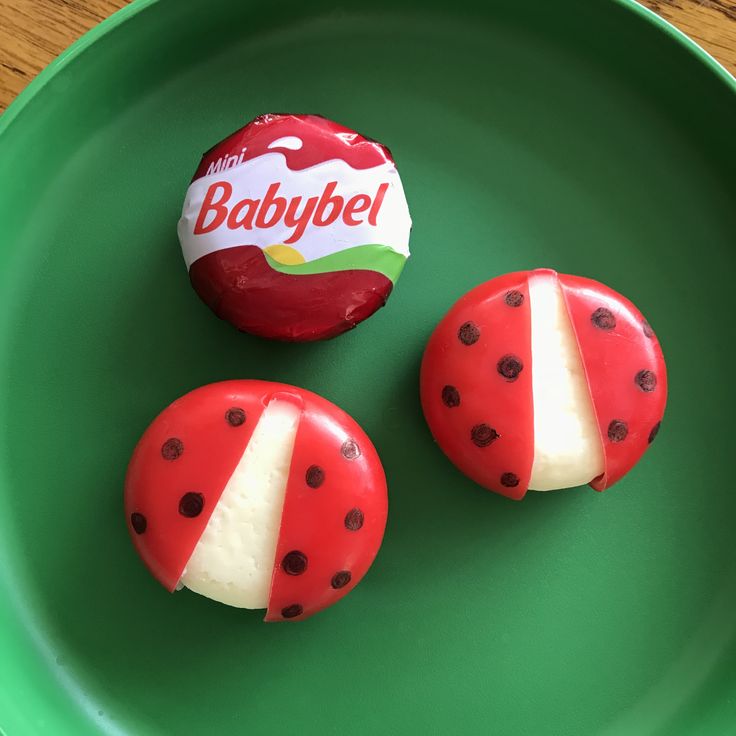 two red and white donuts on a green plate with a babybel candy wrapper