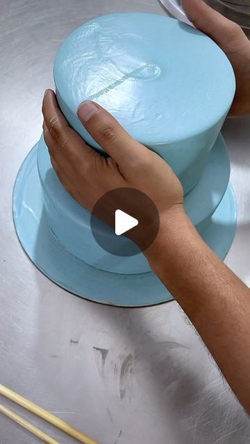 a person is touching the top of a blue cake