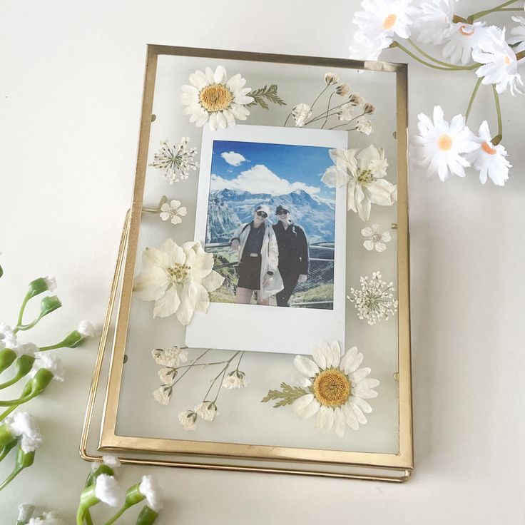 two people standing next to each other with flowers in front of them on a table