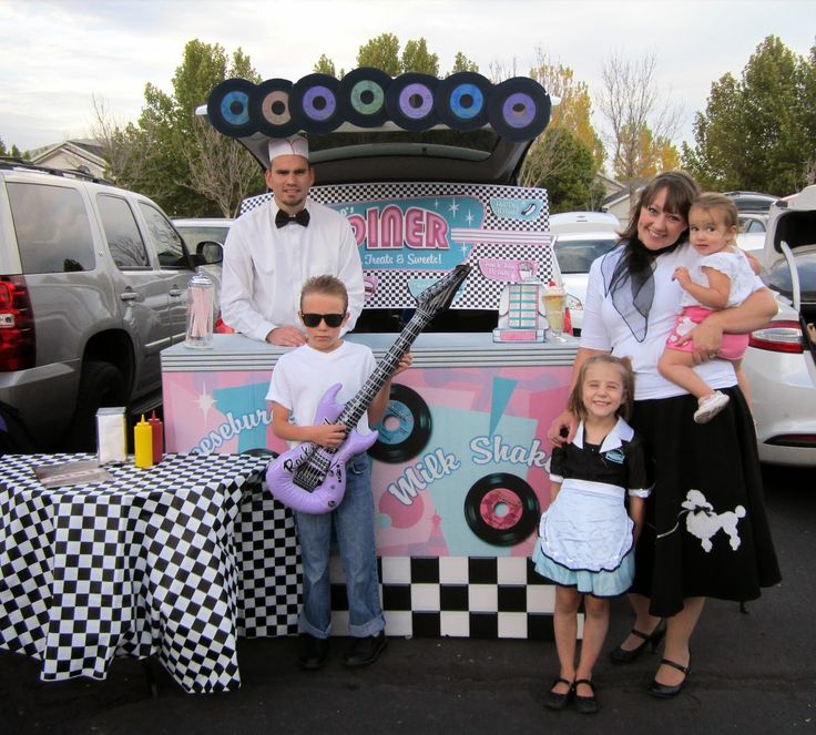 two adults and two children standing in front of a food truck with an electric guitar