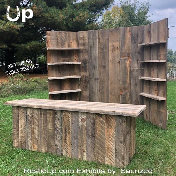 a wooden bench sitting in the grass next to a book shelf and shelving unit