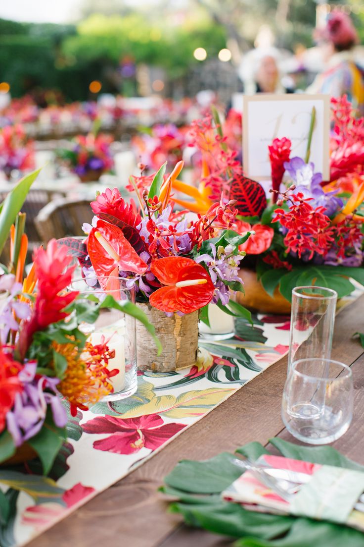 the table is set with colorful flowers and greenery