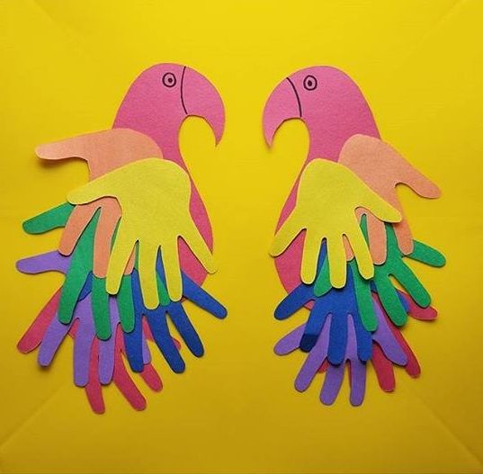 two pink and yellow birds made out of handprinted paper on a yellow background