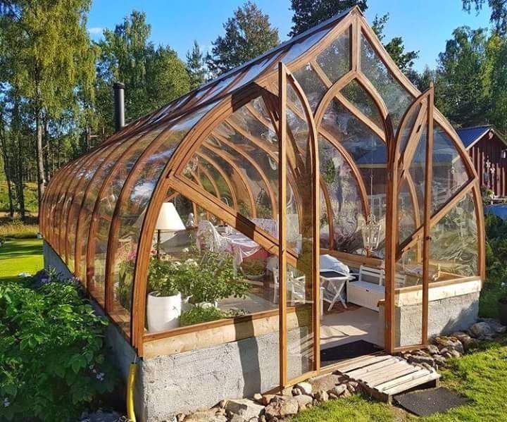 a large wooden greenhouse sitting on top of a lush green field