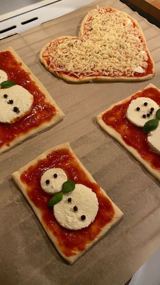 four pizzas with different toppings on them sitting on a baking sheet in the oven