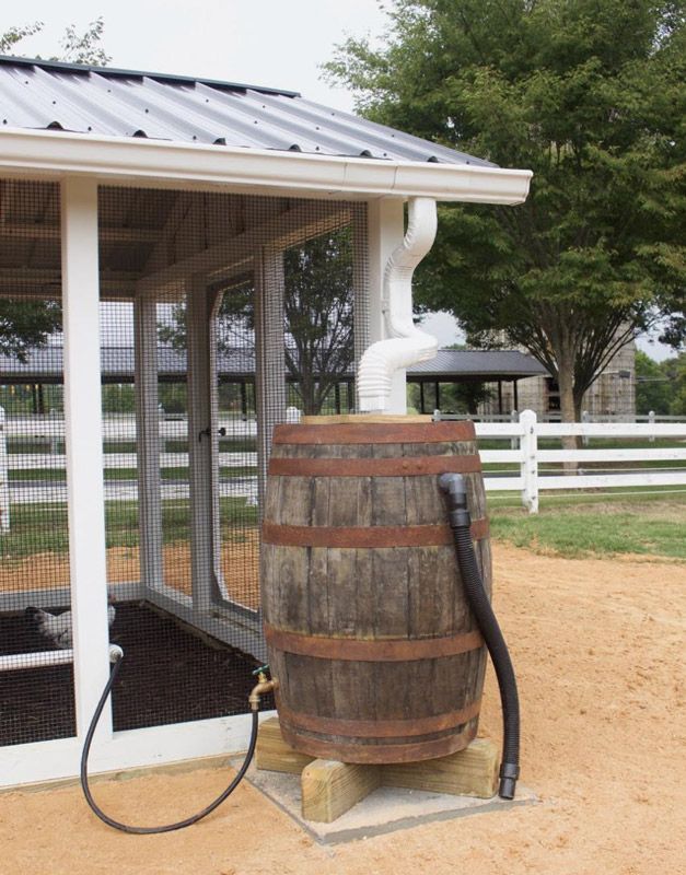 a wooden barrel with a hose attached to it in front of a white fenced area