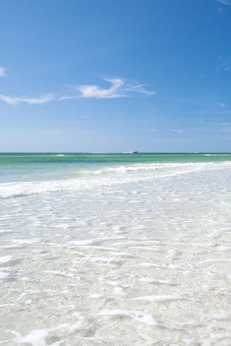 two people walking on the beach with surfboards