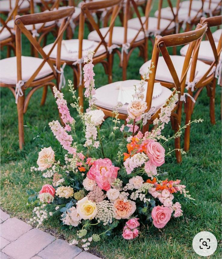 an arrangement of flowers is sitting on the ground in front of chairs