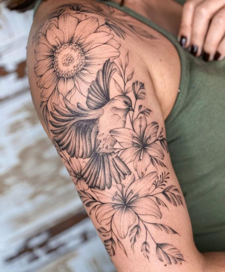 a woman's arm with flowers and a bird tattoo on the left side of her body