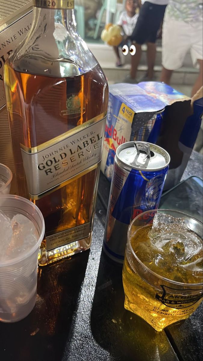 a bottle of alcohol sitting on top of a table next to a cup and container