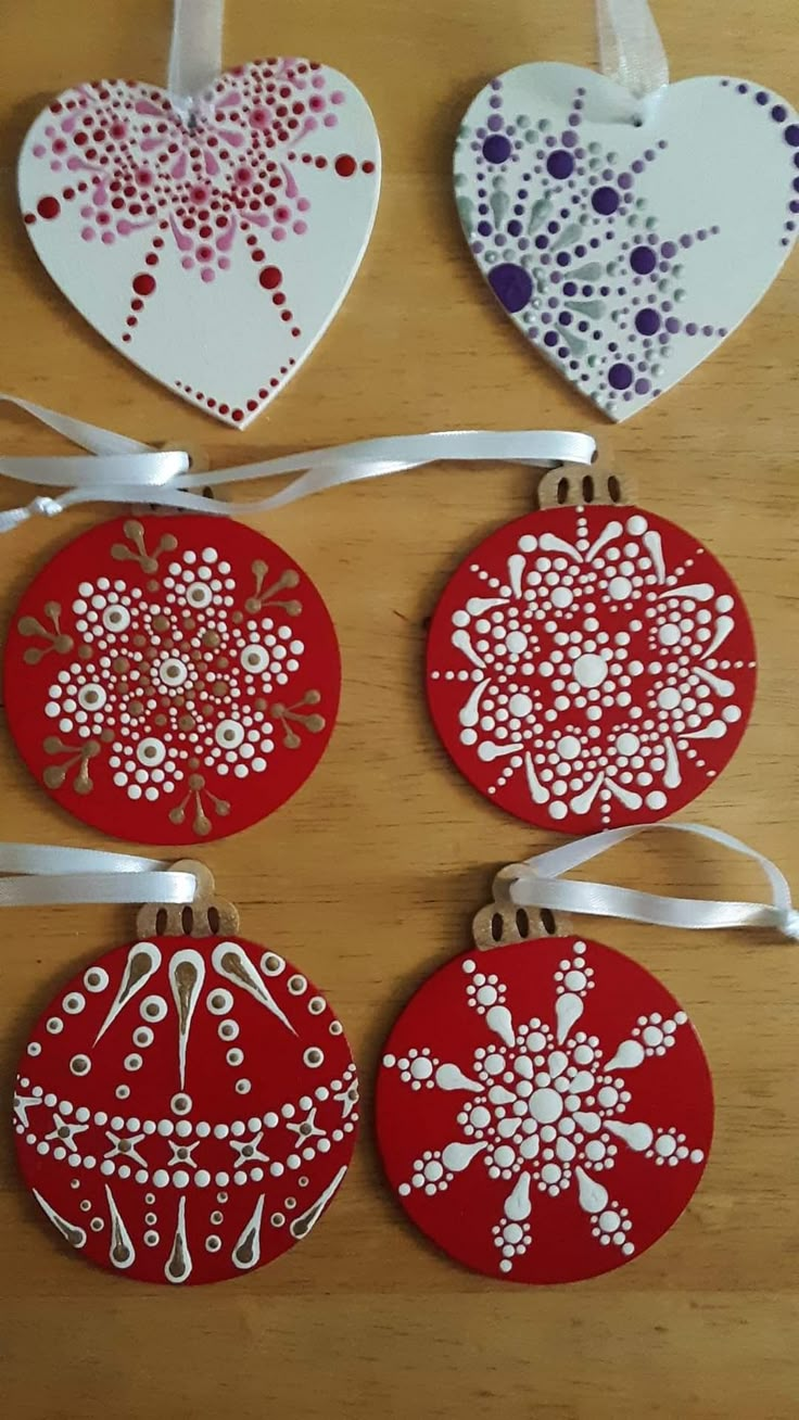 four red and white ornaments are hanging on a wooden table